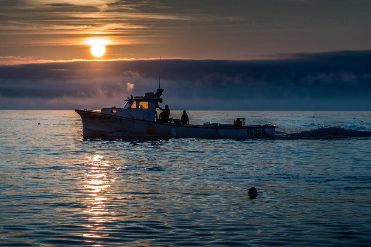 Fischerboot fährt bei Sonnenaufgang auf dem Meer vor Indian Brook, Canada