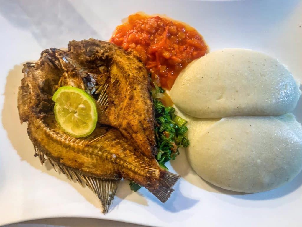 Nsima ist ein ungewürzter Brei,(Cornmeal porridge) der aus Maismehl hergestellt wird. Das Gericht ist Grundnahrungsmittel in Malawi. Hier kombiniert mit Chambo, dem im Malawisee heimischen Fisch aus der Familie der Tilapia / © Foto: Georg Berg