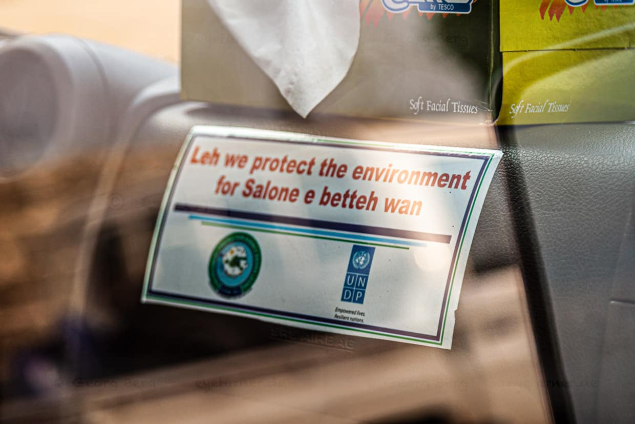 Schützen Sie die Umwelt steht auf einem offiziellen Aufkleber, der für den Schutz der Umwelt wirbt (in Krio-Slang geschrieben). Salone ist der lokale Name für Sierra Leone. / © Foto: Georg Berg