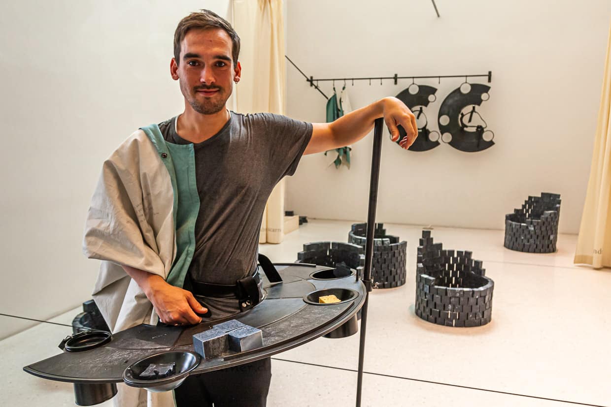 Verkäufer und Erzähler in einem: der Kunststudent Viktor in vollem Ornat für das Kunstprojekt Carved to Flow. Im Hintergrund ein Teil der Seifenproduktion von 45.000 Stück, die in Athen und Kassel für je 20 Euro verkauft werden / © Foto: Georg Berg