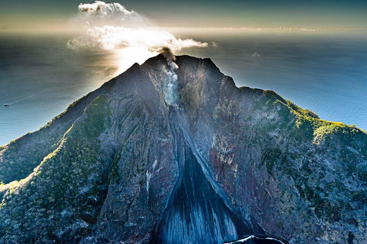 Sogar im Helikopter ist der Schwefelgeruch des aktiven Vulkans Batu Tara auf der Insel Komba wahrzunehmen. Klein am linken Bildrand ist die True North zu sehen / © Foto: Georg Berg