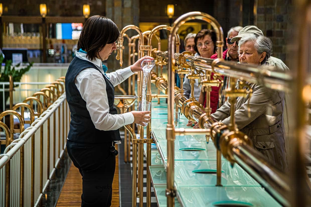Schönes Ritual: Zum Nachmittags-Konzert lassen sich die Kurgäste Heilwasser einschänken. Das Orchester spielt, die Halle ist schön wie immer und das Wasser schmeckt nicht wirklich gut, aber in kleinen Schlucken und mit der nötigen Muße lässt es sich trinken und dem eigenen Körper was Gutes tun / © Foto: Georg Berg