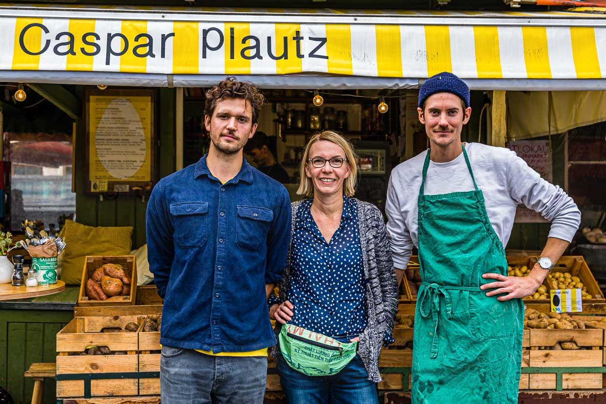 Dominik Klier und Theo Lindinger zusammen mit Reporterin Angela Berg vor den Speisekartoffeln von Caspar Plautz. Zur Zeit ist die Auswahl auf 12 Sorten begrenzt. Zum Herbst hin weitet sich das Angebot auf bis zu 25 Sorten aus / © Foto: Georg Berg