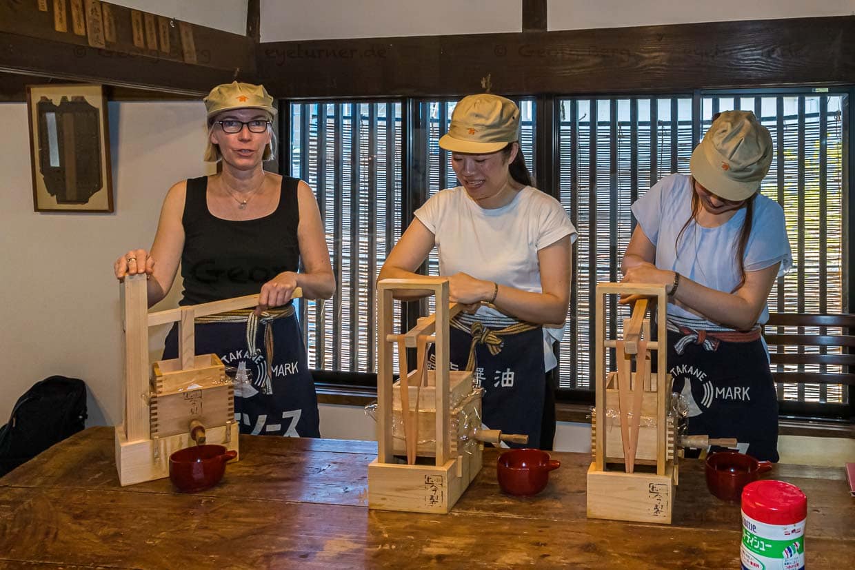 Schürze an und dann die Miniatur-Presse vorbereiten. Durch insgesamt drei Tuchlagen mit mehreren Schichten wird dickflüssiges Moromi, die Trockenmaische, gepresst / © Foto: Georg Berg