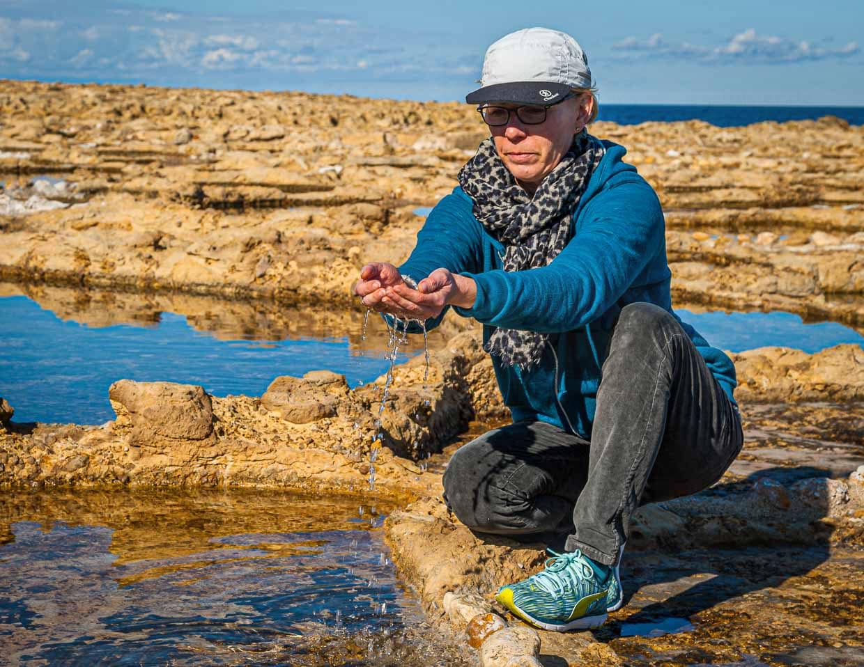 Angela Berg schöpft das salzhaltige Wasser aus einer antiken Salzpfanne / © Foto: Georg Berg