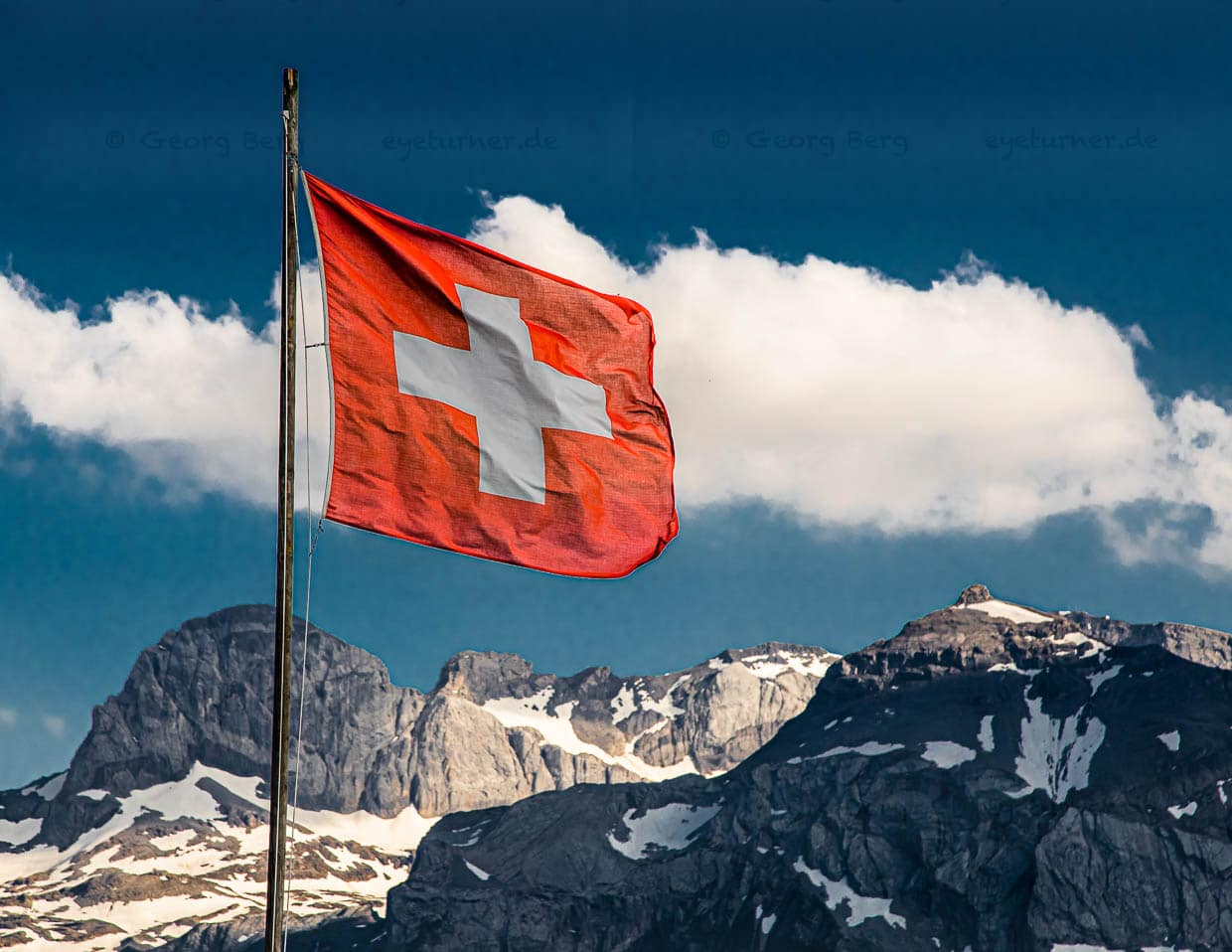 Schweizer Fahne im Restaurant Bühlberg. Hoch oben auf dem Bühlberg steht das zum Lenkerhof gehörende Bergrestaurant, von dessen Terrasse aus Sie herzhafte Speisen und eine herrliche Aussicht auf die Bergkette, die den Kanton Bern vom Wallis trennt, genießen können / © Foto: Georg Berg