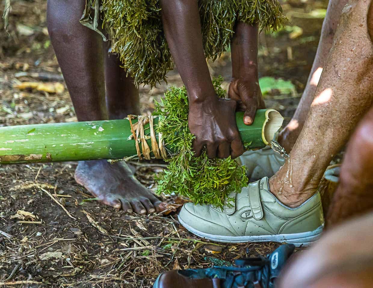 Auf ungewöhnliche Art werden Neuankömmlinge auf Bougainville willkommen geheißen. Mit Wasser aus einem Bambusrohr werden zur Inseltaufe die Füße gewaschen / © Foto: Georg Berg