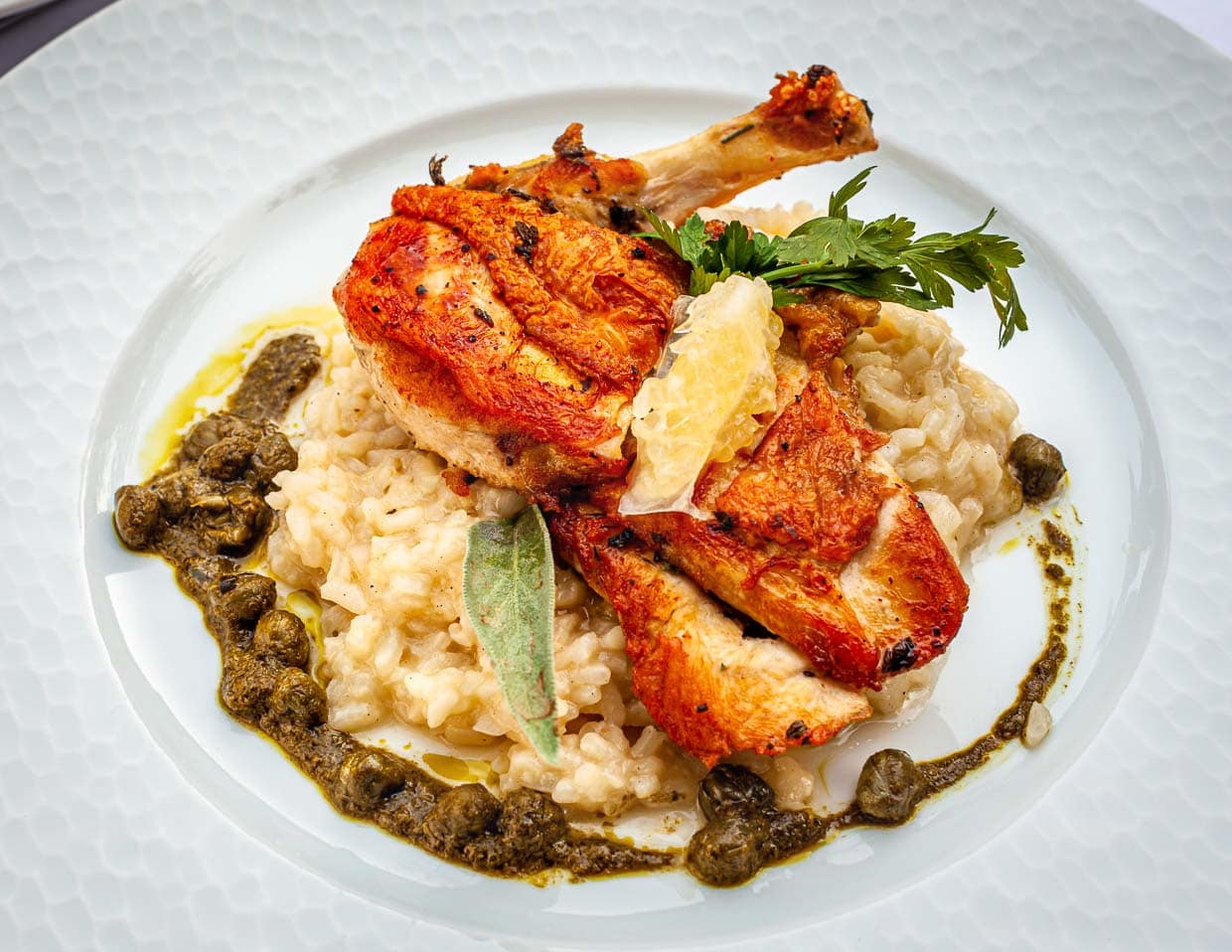 Ein Gericht, auf das man sich freuen kann: Petto di Faraona. Ein umwerfend zitroniges Perlhuhn mit Kapern-Basilikum-Salsa und Zitronen-Risotto / © Foto: Georg Berg