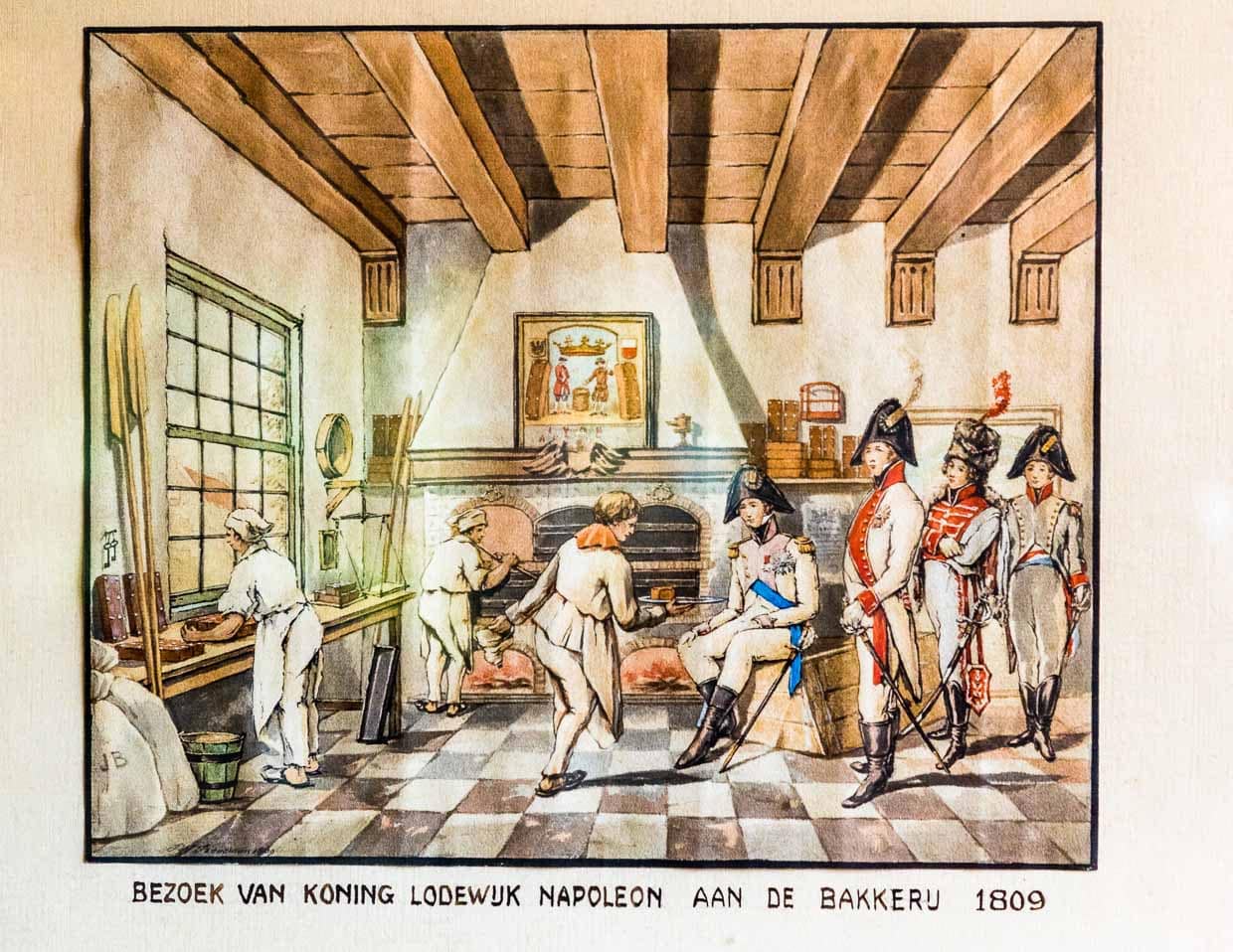 Das Bild hängt im Deventer Koekwinkel und zeigt eine historische Szene aus dem Jahre 1809. Von 1806 bis 1810 war Lodewijk Napoleon König des von seinem Bruder Kaiser Napoleon geschaffenen Königreichs Holland. Der König interessierte sich für den berühmten Kuchen und ließ sich die Herstellung zeigen. Begeistert gab er eine größere Bestellung auf und wollte ohne zu zahlen seine Kutsche besteigen.Die Bäckersgattin zupfte ihn daraufhin am Ärmel und forderte erfolgreich den Geldbetrag ein / © Foto: Georg Berg