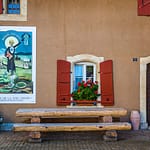 Absinth in Frankreich und der Schweiz. In Motiers im Schweizer Kanton Neuchâtel befindet sich das unterhaltsame Absinthmuseum, und an einigen Häuserwänden der Stadt erinnern historische Plakate an die Zeit der Prohibition / © Foto: Georg Berg