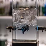 Moderne kalte Quelle für Absinth. Früher tropfte das eiskalte Wasser mit einem Tropfen pro Minute über den Zuckerwürfel und durch den Löffel in den zimmerwarmen Alkohol. Jeder Tropfen hinterließ eine milchig-grüne Trübung im Glas / © Foto: Georg Berg