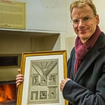 Matthias Trum von der Schlenkerla Bräu vor dem Holzofen mit dem das Grünmalz betrocknet wird. In der Hand hält er eine Zeichnung zur industriellen Malztrocknung nach Sir Nicholas Halse / © Foto: Georg Berg