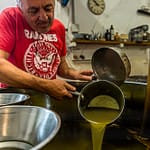 Nach dem Pressvorgang, steht das Wasser-Öl-Gemisch in offenen Behältern. Nach gut einer Stunde beginnt Fabrice Godet damit, das oben schwimmende Olivenöl abzuschöpfen. Das Fruchtwasser sinkt nach unten / © Foto: Georg Berg