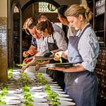 Küchenteam bei der Garnitur vieler Tellergerichten auf dem Flur / © Foto: Georg Berg
