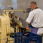 Maschinelle Verpackung von Nuss-Nougat-Pralinen in gold und rot gesteiften Papilloten in der Chocolaterie Frigoulette in Beaufort-sur-Gervanne im Val de Drôme / © Foto: Georg Berg