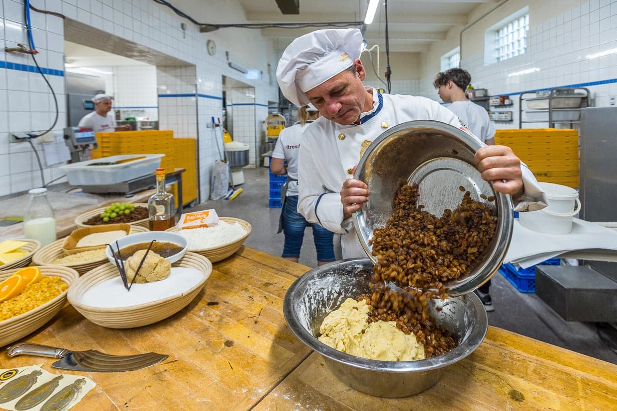 Bäckermeister Tino Gierig gibt die in braunem Rum eingelegten Sultaninen zum Stollenteig. 60 Prozent der Masse machen hier die Sultaninen aus / © Foto: Georg Berg