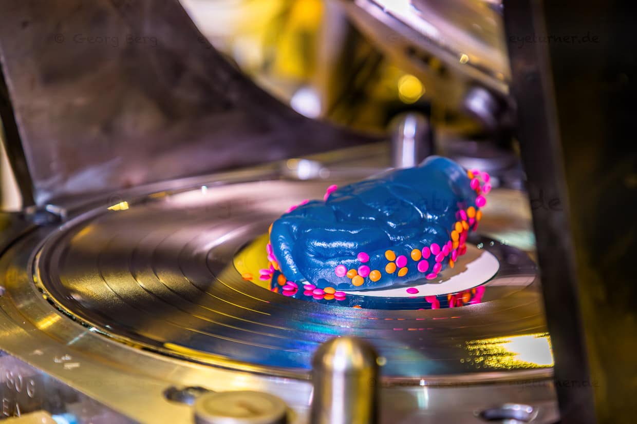 Vor dem Pressen kann der Puck mit farbigem Granulat "panniert" werden, je nachdem, welches Design der Kunde wünscht. Die Möglichkeiten sind vielfältig: einfarbig, mehrfarbig, gemustert. / © Foto: Georg Berg