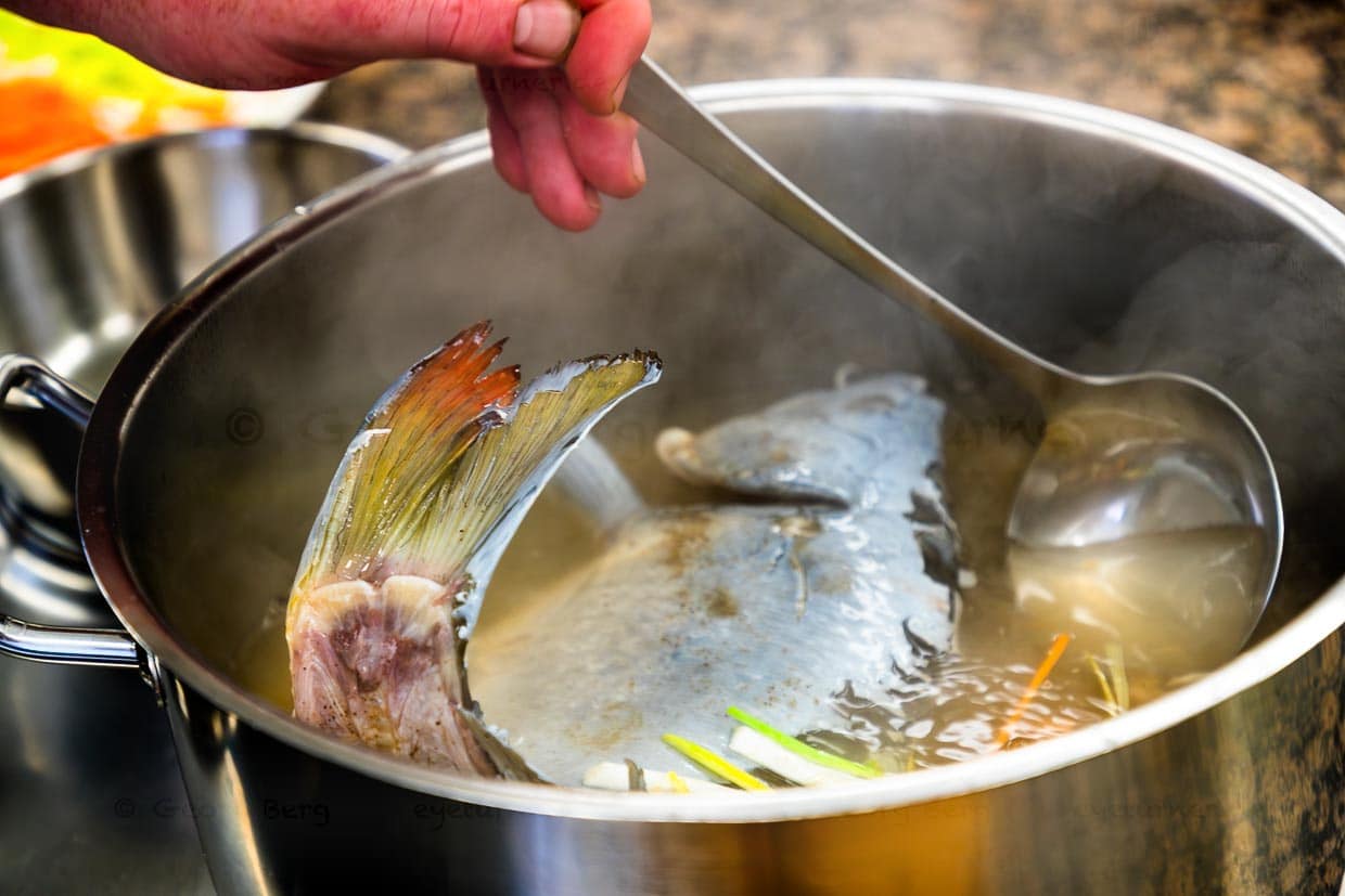Halbierter Karpfen in einem Sud aus Essig, Wasser und Gemüse. Nur wenn der Karpfen frisch geschlachtet ist, verfärbt sich die Schleimschicht auf der Haut blau. Essig im Sud stabilisiert die blaue Farbe. Blaukochen ist eine tradktionelle Zubereitung für Süßwasserfische wie Karpfen, Schleie oder Forelle / © Foto: Georg Berg