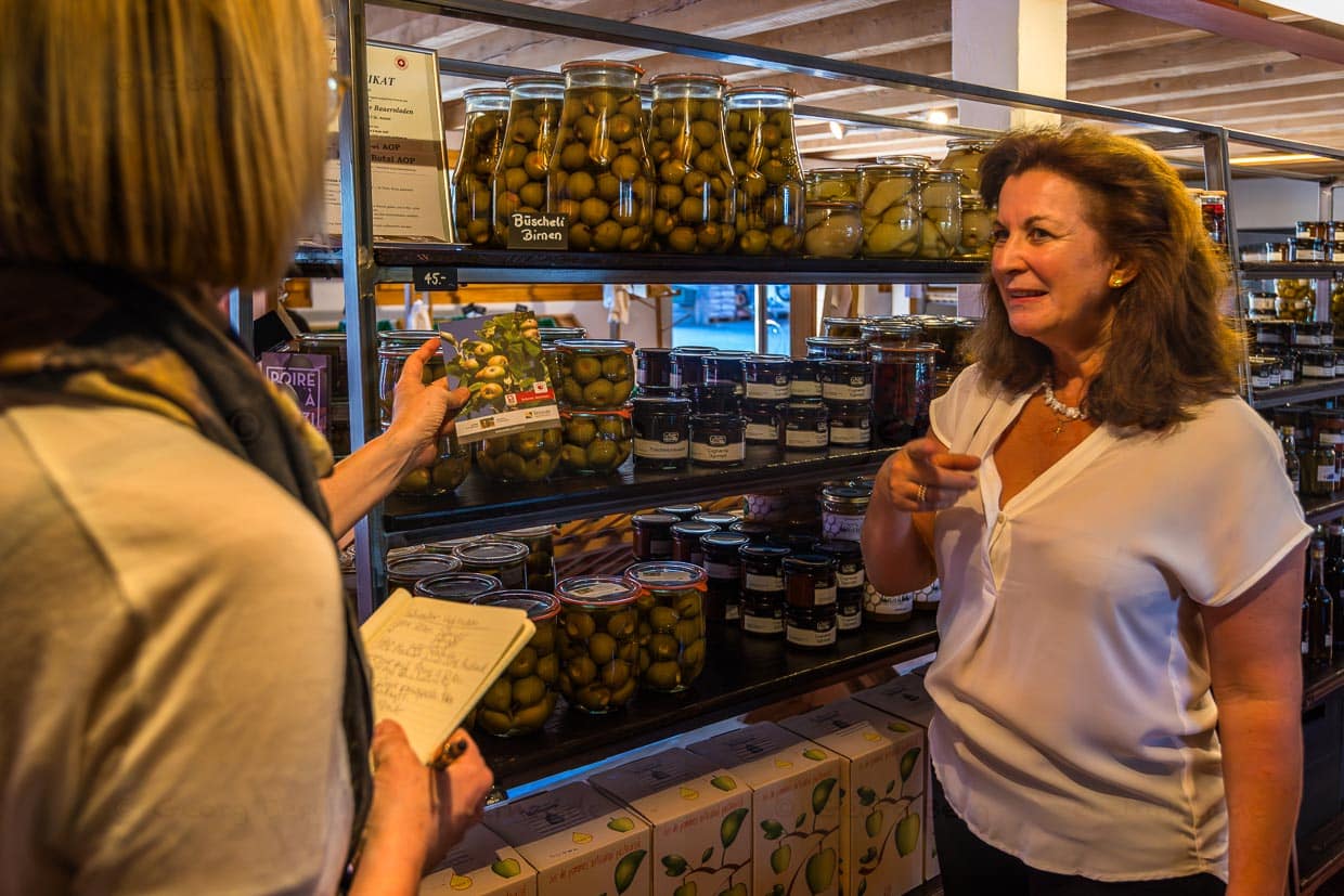 Andrea Schwaller, Eigentümerin von Schwallers`s Sensler Bauernladen in St. Antoni beschreibt die Verarbeitung der Büschelbirne. Ende Juli ist die Ernte, innerhalb von zwei Wochen müssen die kleinen Birnen verarbeitet werden / © Foto: Georg Berg