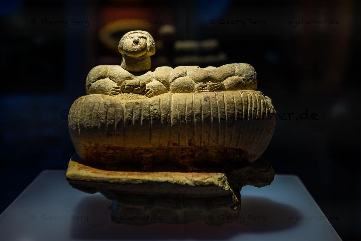 Eine Skulptur, die zwei korpulente Menschen, die auf einem Korbsofa sitzen, darstellt, ist einzigartig auf Malta und unterscheidet sich auch von anderen mediterranen Skulpturformen. Sie haben ungleiche Zopffrisuren. Der erhaltene Kopf trägt einen aufwendigen Haarknoten mit herabhängendem Zopf. Die eine Figur trägt in der Hand eine kleinere Darstellung ihrer selbst, die andere ein kleines Gefäß.Die Ġgantija-Tempel auf der Insel Gozo gehören zur UNESCO Welterbestätte Megalithische Tempel von Malta und den ältesten noch halbwegs erhaltenen freistehenden Gebäuden der Welt / © Foto: Georg Berg