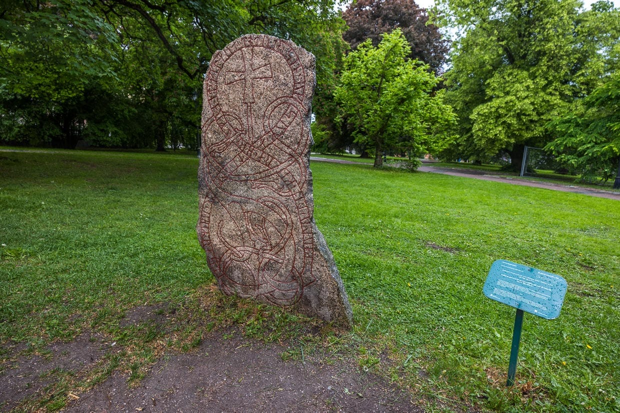 Pierre runique dans le parc universitaire d'Uppsala. On y trouve au total 16 pierres runiques originales de l'époque viking. Parmi elles, des exemplaires particuliers comme cette pierre qui raconte que Güllög a fait construire un pont en mémoire de sa fille décédée. Les pierres runiques étaient chères et généralement érigées pour les hommes / © Photo : Georg Berg