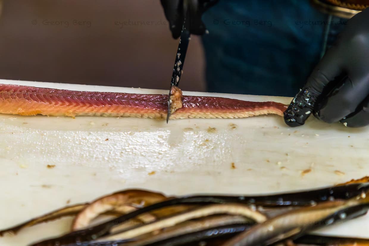 Matthias Föh enlève la couche de graisse sur le filet d'anguille, ainsi l'anguille fumée est plus digeste / © Photo : Georg Berg