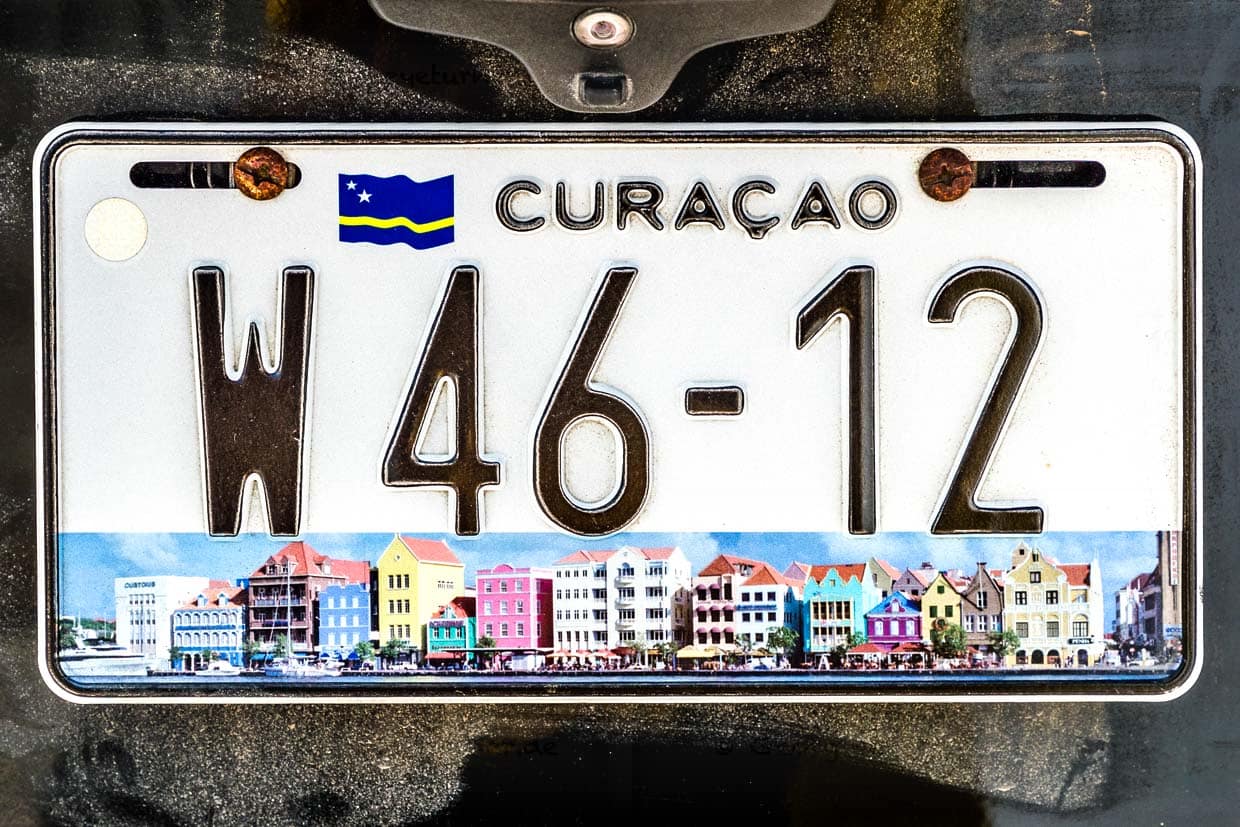 A Curaçao, les plaques d'immatriculation des voitures sous le drapeau national montrent aussi les façades colorées des maisons de la Handelskade à Willemstad, la capitale / © Photo : Georg Berg