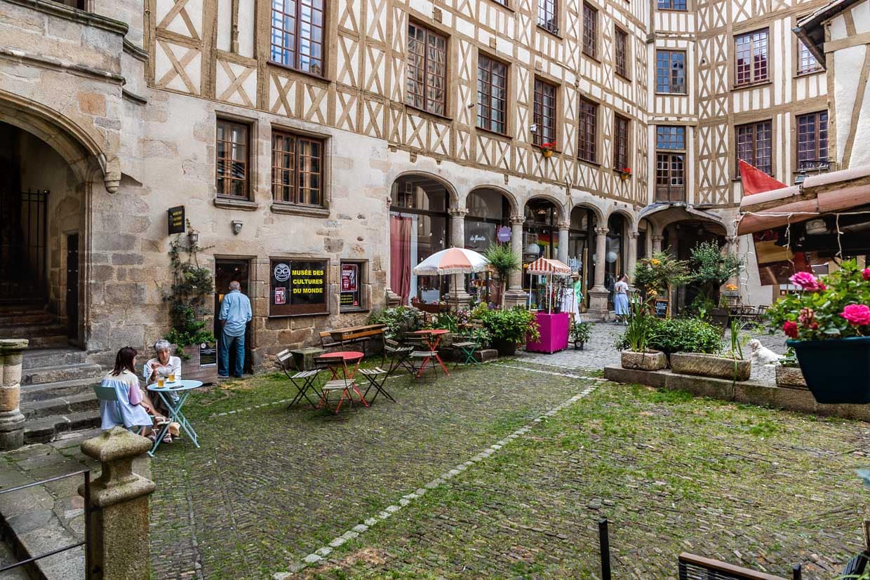 Cour intérieure La cour du Temple, dans le vieux Limoges, a une histoire particulière en tant que lieu de rencontre central de l'ancien quartier artisanal et commercial de la ville. La cour intérieure est reliée à la rue du Consulat par un couloir et s'ouvre sur un impressionnant ensemble de maisons en granit et à colombages avec des arcades et un élégant escalier Renaissance. Aujourd'hui, la cour abrite de petits cafés et des boutiques / © Photo : Georg Berg