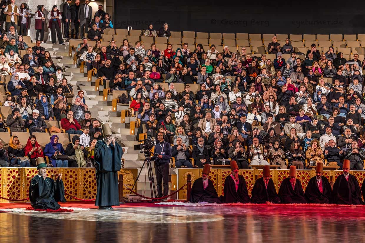 Das Ende der Şeb-i Arus-Zeremonie im 3.000 Personen fassenden Mevlana Kültür Merkezi wird mit einer Koranrezitation eingeleitet. Die Derwische sind nach ihrem Wirbeltanz wieder in ihre schwarzen Mäntel gehüllt / © Foto: Georg Berg