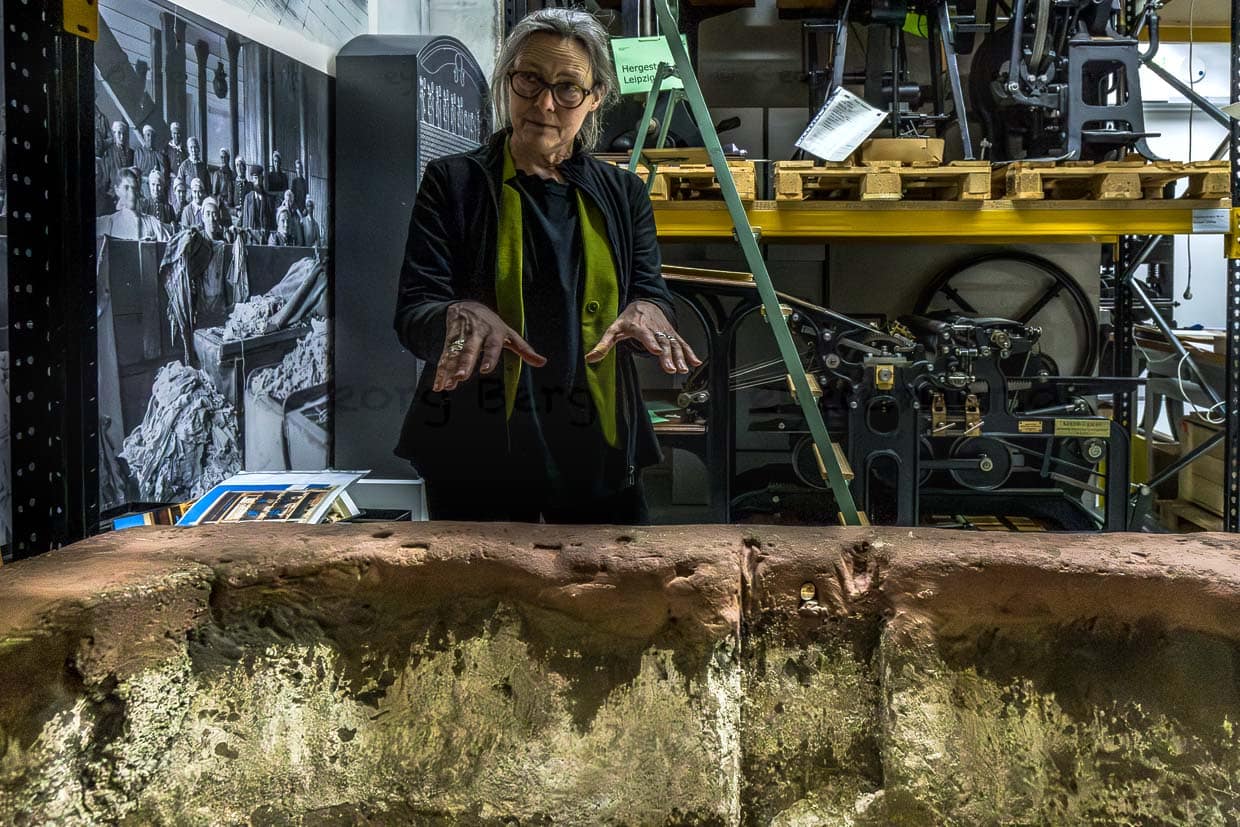 Frau mit Brille präsentiert ein Objekt in einem Museum in Leipzig, Germany