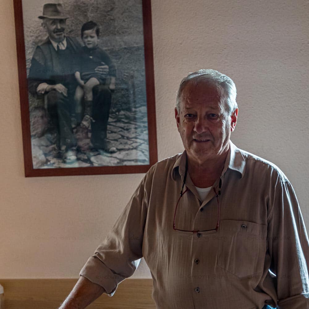 Geurino Pifaretti, Inhaber der Osteria Manciana vor dem Foto, das ihn zusammen mit seinem Großvater zeigt / © Foto: Georg Berg
