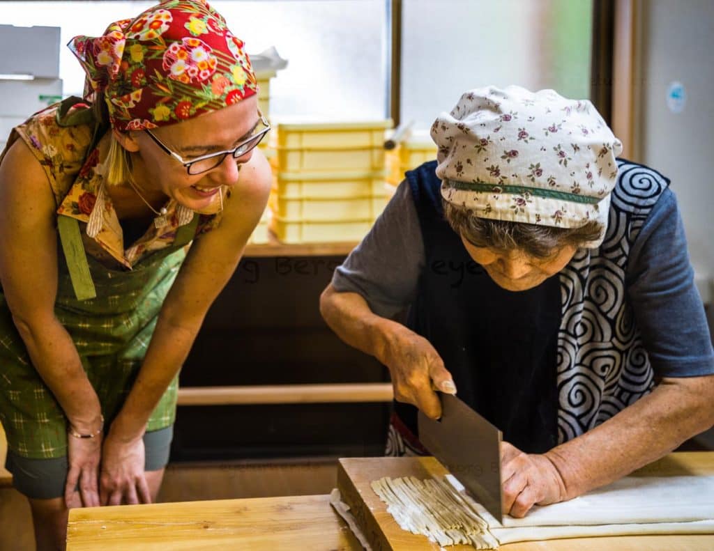Sumiko Sano zeigt wie dick die Nudeln werden sollen. Was das Foto nicht verrät, ist die Geschwindigkeit, mit der das Messer durch den Teig fährt / © Foto: Georg Berg