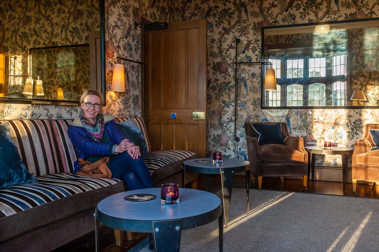 Im Damen-Salon – als wäre der nicht schon schön genug – scheint die Abendsonne über den englischen Rasen durch die Fenster. Auch hier handbemalte antike Tapeten, alte Spiegel und moderne Lampen sowie ausgefallenen Beistelltische neben alten Sitzmöbeln / © Foto: Georg Berg