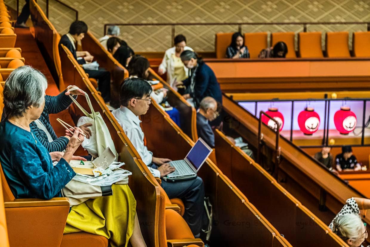 Vorhang zu - Bento auf. Im Kabuki Theater in Tokio sind die Zuschauer bestens vorbereitet. Statt feiner Handtaschen führt man hier geräumige Stoffbeutel mit sich. Aber auch das Klischee des stets arbeitsamen Japaners wird beim Betrachten dieses Fotos bedient / © Foto: Georg Berg