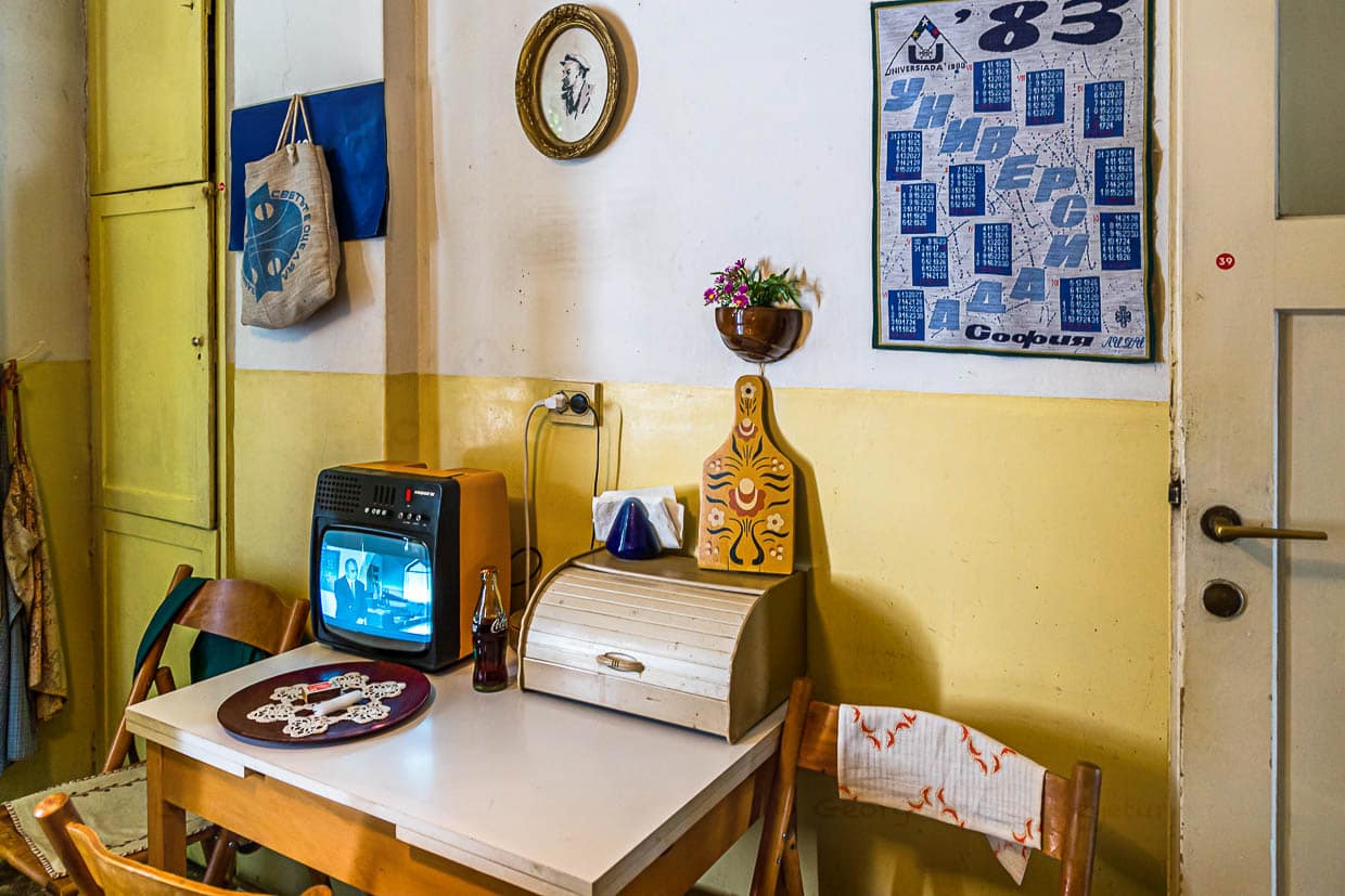 Stoisch hört sich der gehäkelte Lenin in der Küche der "Red Flat" die Dauerschleife an, mit der das bulgarische Fernsehen die Eröffnung der ersten Coca Cola Abfüllanlage des Ostblocks rühmt / © Foto: Georg Berg