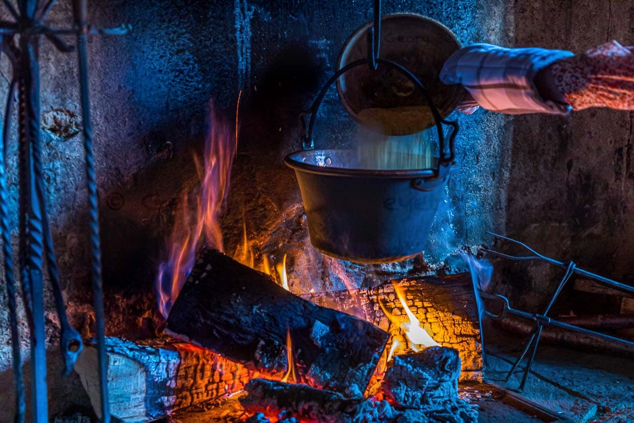 In Cerentino kann man im aufwendig renovierten historischen Patrizierhaus Cà Vegia wohnen, mit jahrhundertealten Originalmöbeln, aber ohne Strom. Polenta wird über dem offenen Feuer zubereitet, Circolo della Rovana, Schweiz / © Foto: Georg Berg