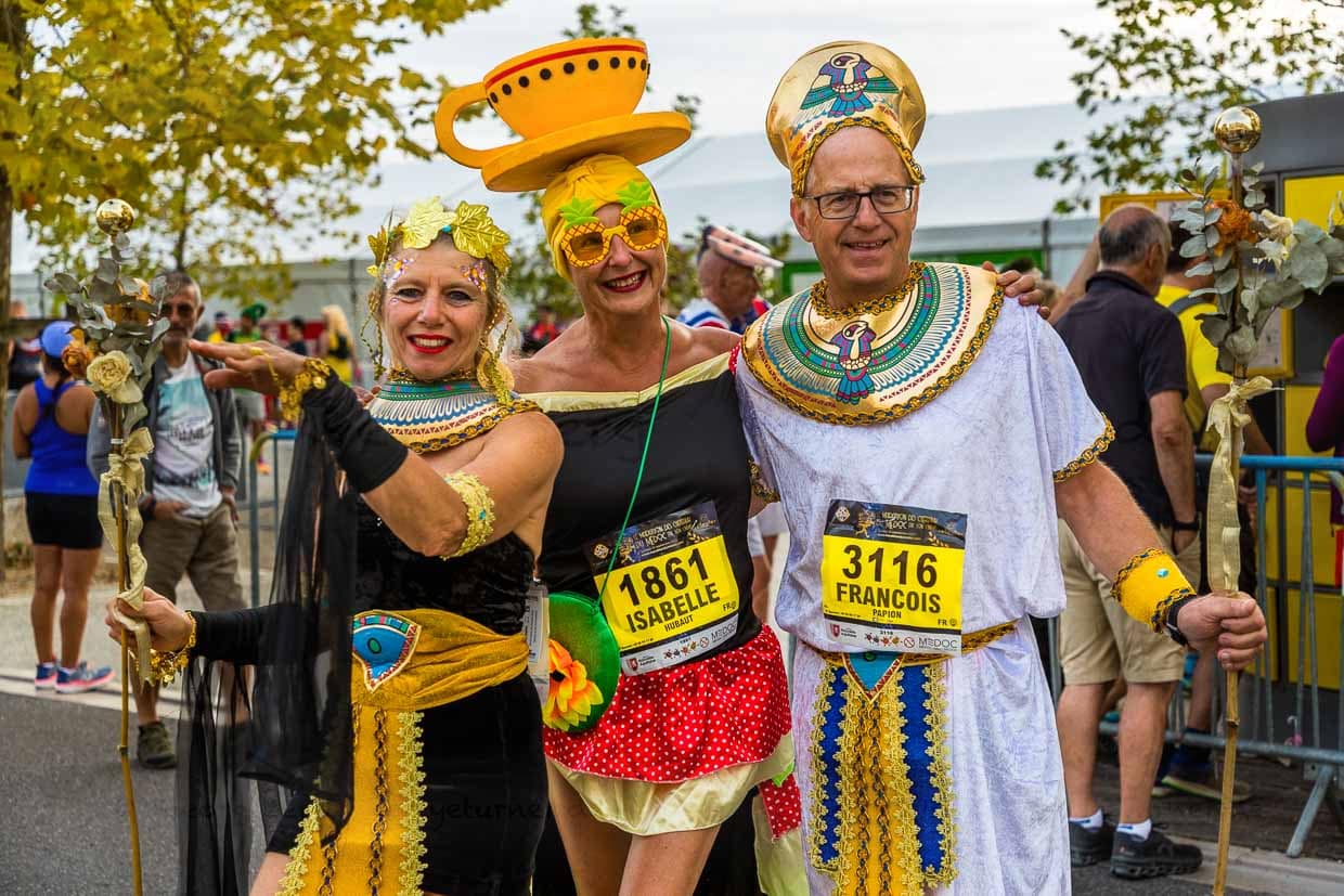 Vor dem Start des Marathon des Chateaux du Medoc gibt es das Defilee der Kostüme. Aus Lautsprechern schallt berühmte Filmmusik und auf der Straße am Ufer der Gironde trifft ein ägyptisches Herrscherpaar auf eine gut gelaunte Teetasse / © Foto: Georg Berg