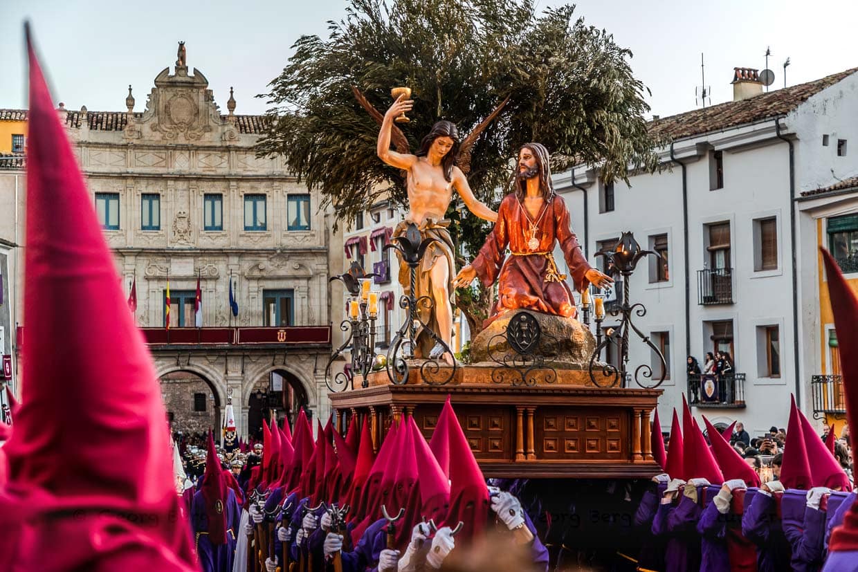 Procesión en España con Jesús y un ángel en una carroza; los peregrinos visten túnicas rojas y moradas / © Foto: Georg Berg