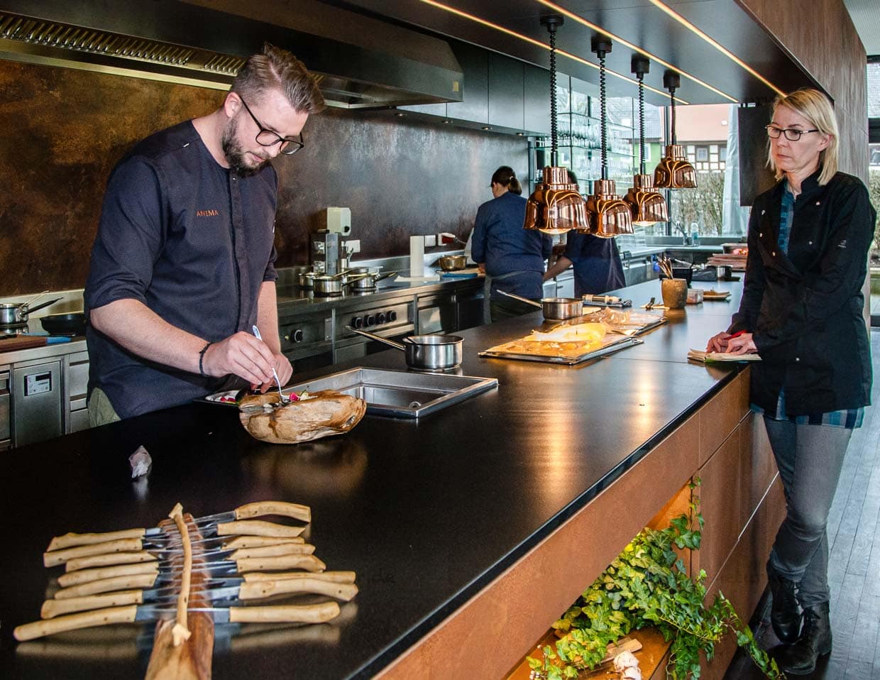 Das Team von Heiko Lacher ist im wahrsten Sinne überschaubar, denn der Sternekoch und seine beiden Köche hantieren hinter einer langen offenen Küche, die den ganzen Gastraum flankiert / © Foto: Georg Berg