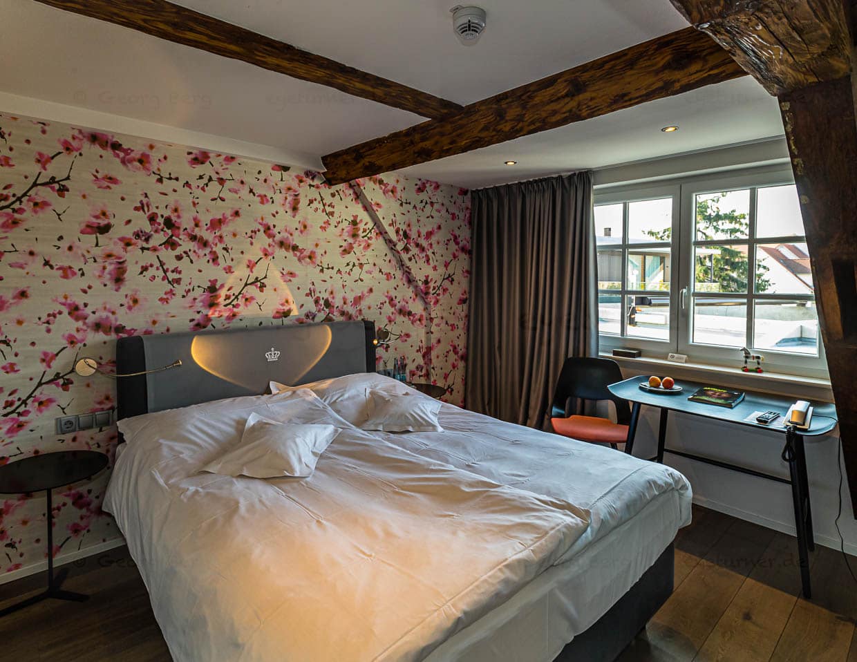 Im historischen Haupthaus zeigt sich, wie gut alt und neu harmonieren. Die Holzbalken wurden freigelegt und lackiert. Sie stehen in Kontrast zu den mit rund 60 Jahren vergleichsweise jungen Designklassikern von Charles und Ray Eames, Jean Prouvé oder Isamu Noguchi / © Foto: Georg Berg