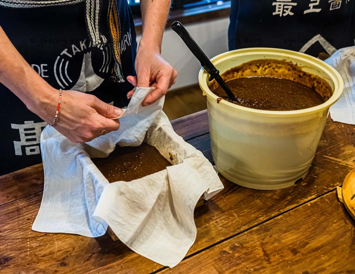 Nach der Führung durch die Manufaktur geht es im wahrsten Sinne des Wortes ans „Eingemachte“. Moromi wird den Workshop-Teilnehmern im kleinen Eimer vorgesetzt. Im Kleinen findet nun statt, was in der Manufaktur mit 1.000 Litern Moromi passiert. Durch die Filterpressung kommen am Ende 800 Liter Sojasauce heraus / © Foto: Georg Berg