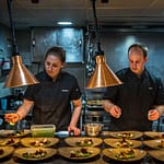 Mit Standfestigkeit und ruhiger Hand: Martina und Gavin richten in der Kombüse trotz Seegang das Hauptgericht an / © Foto: Georg Berg