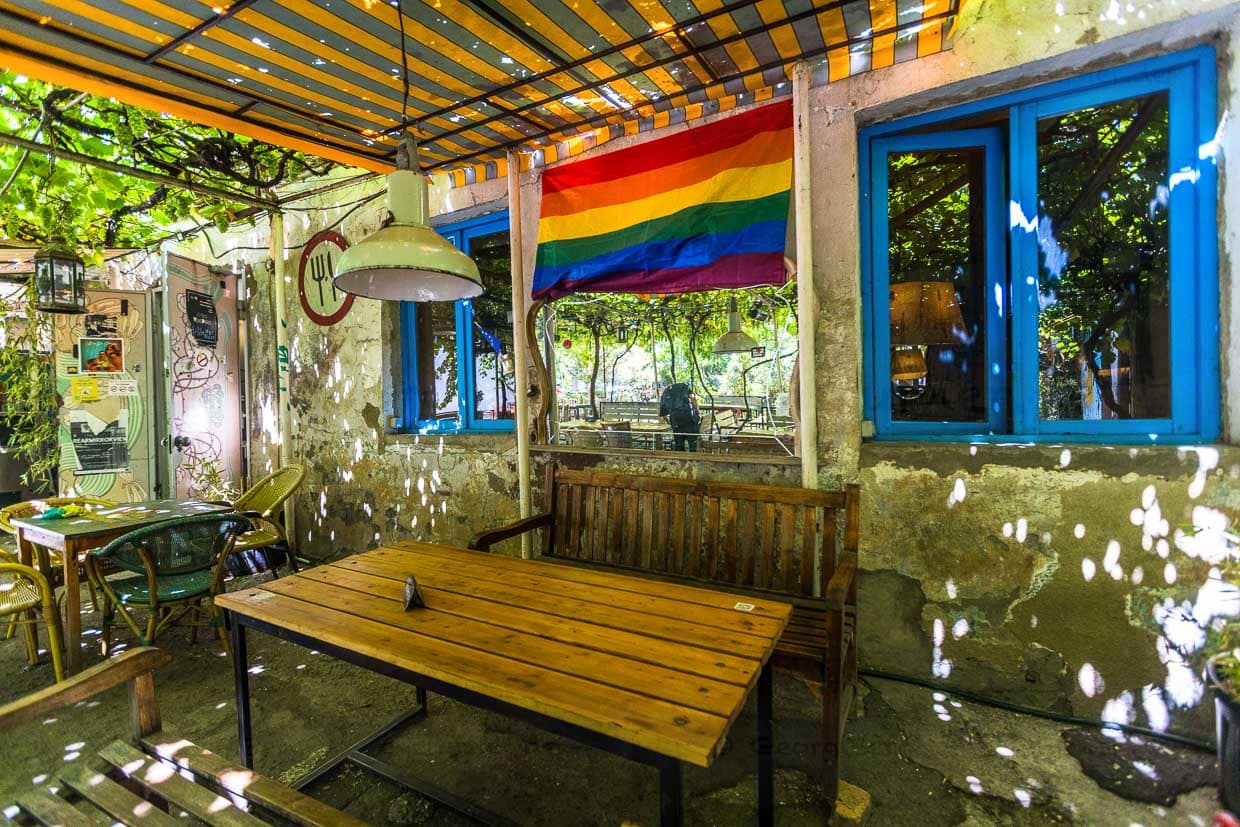 Im Sofia Melnikova’s Fantastic Douqan Restaurant hängt Regenbogenflagge an der Wand. Sonnenlicht fällt durch ein Vordach und Weinreben. Der Ort befindet sich in Tbilisi, Georgien / © Foto: Georg Berg