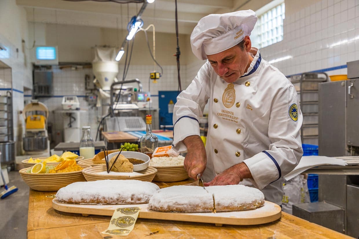 Bäckermeister Tino Gierig schneidet einen Original Dresdner Christstollen an. Stollen werden immer in der Mitte angeschnitten, so kann man die beiden Hälften zum Lagern wieder zusammenschieben und die Schnittstellen trocknen nicht aus / © Foto: Georg Berg