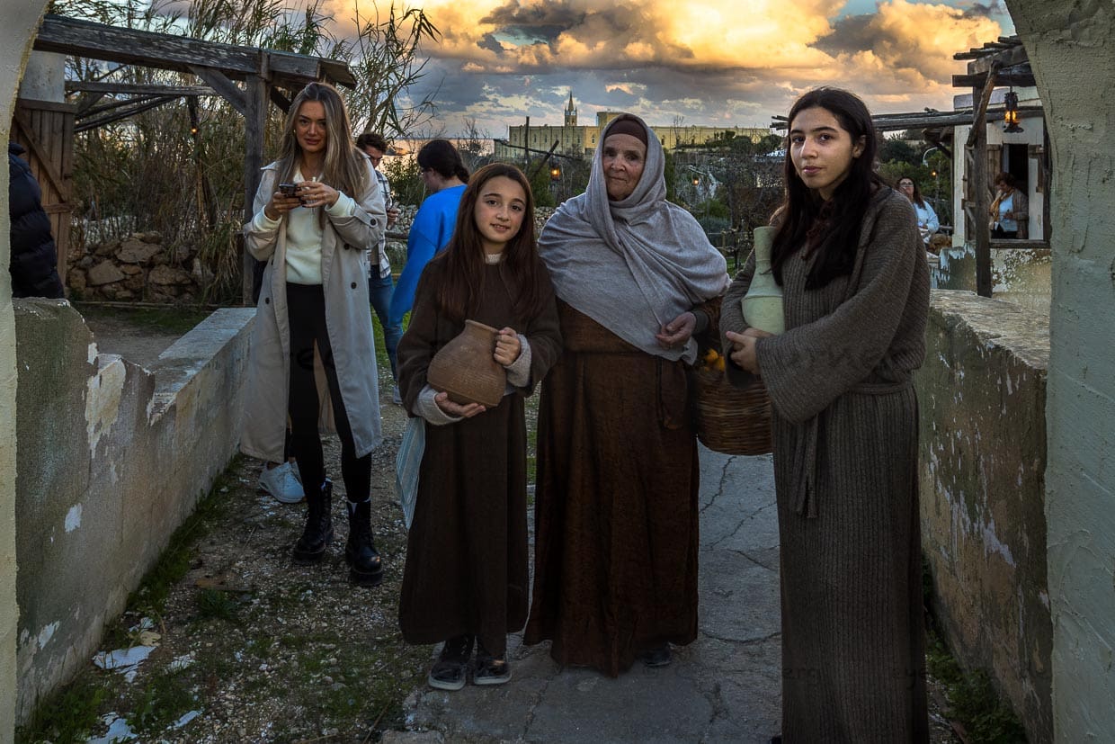 Darsteller im Bethlehem Dorf Għajnsielem auf Gozo. Hier eine Großmutter mit ihren Enkeltöchtern beim Einkauf im Dorf. Kleidung und Alltagsgegenstände wie vor 2.000 Jahren. Besucher laufen durch die Gassen des nachgebauten Dorfes / © Foto: Georg Berg