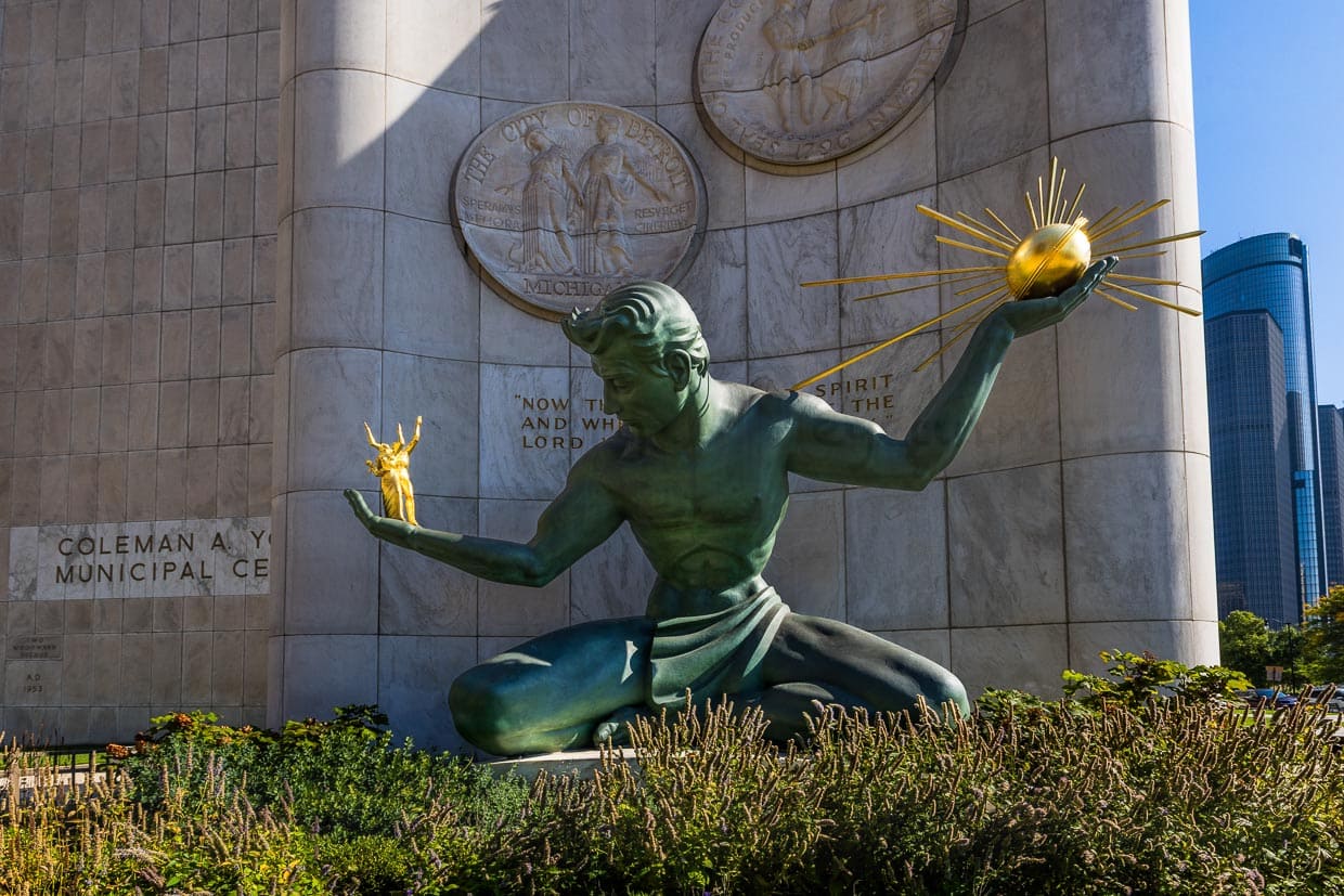 Denkmal The Spirit of Detroit, Bronzestatue von Marshall Fredericks am Coleman A. Young Municipal Center an der Woodward Avenue in Detroit, Michigan. In der linken Hand hält die sitzende Figur eine vergoldete Bronzekugel, die Strahlen aussendet und Gott symbolisiert. Die Menschen in der rechten Hand sind eine Familiengruppe, die für alle menschlichen Beziehungen steht / © Foto: Georg Berg