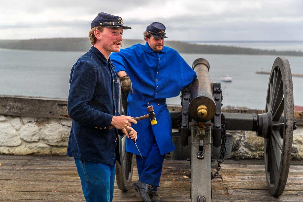 Auf einer Geschützstellung mit alter Kanone demonstrieren zwei Darsteller in Uniform das Abfeuern einer Kanonenkugel / © Foto: Georg Berg