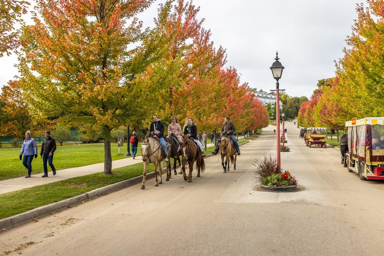 Where Horse is King. Touristen reiten auf Pferden dier Cadotte Avenue entlang. Mackinac Island ist eine autofreie Insel. Im Juli 1898 beschloss der Gemeinderat der Dorfes, dass das Führen von pferdelosen Kutschen in den Grenzen des Dorfes Mackinac verboten ist / © Foto: Georg Berg