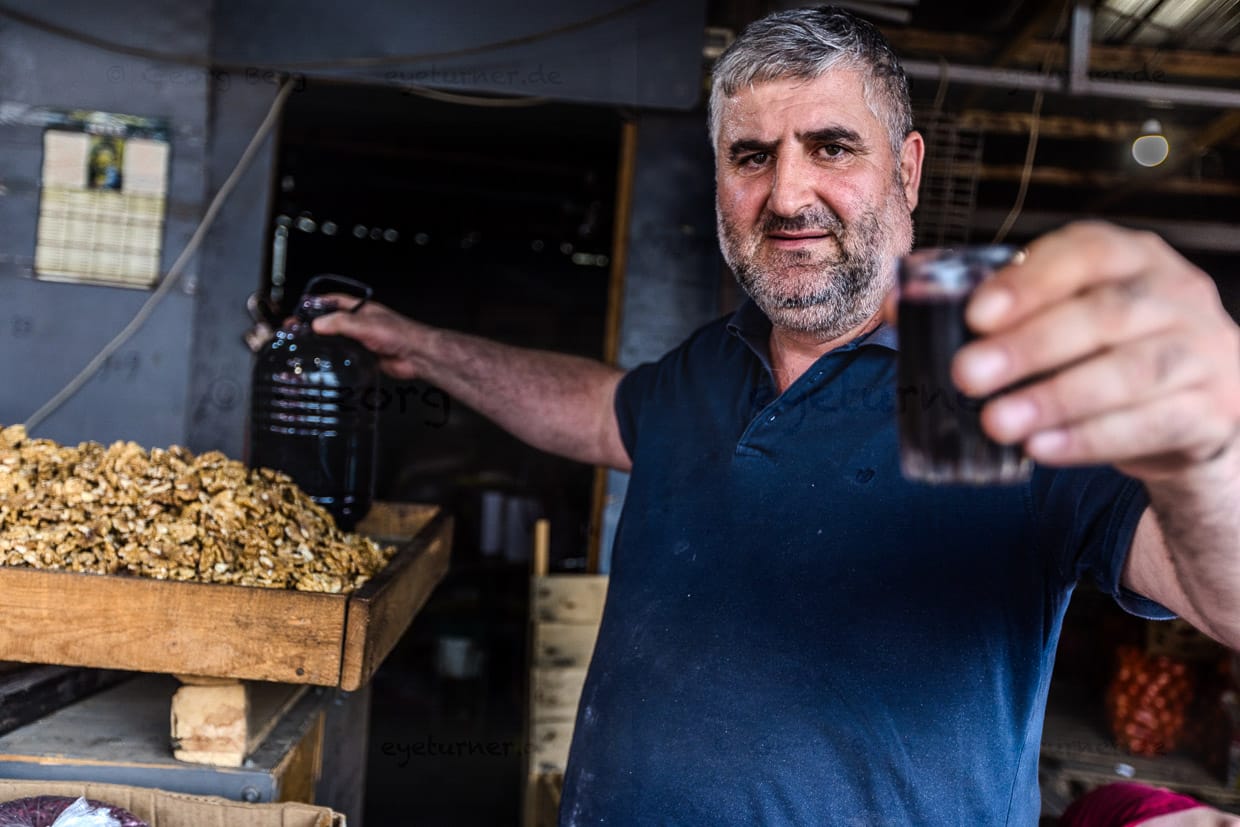 Ein Nussverkäufer bietet Wein zum Verkosten an. Früher gab es auf dem Dezerter Basar eine ganze Weinabteilung. Heute gibt es nur noch wenige Weinhändler / © Foto: Georg Berg