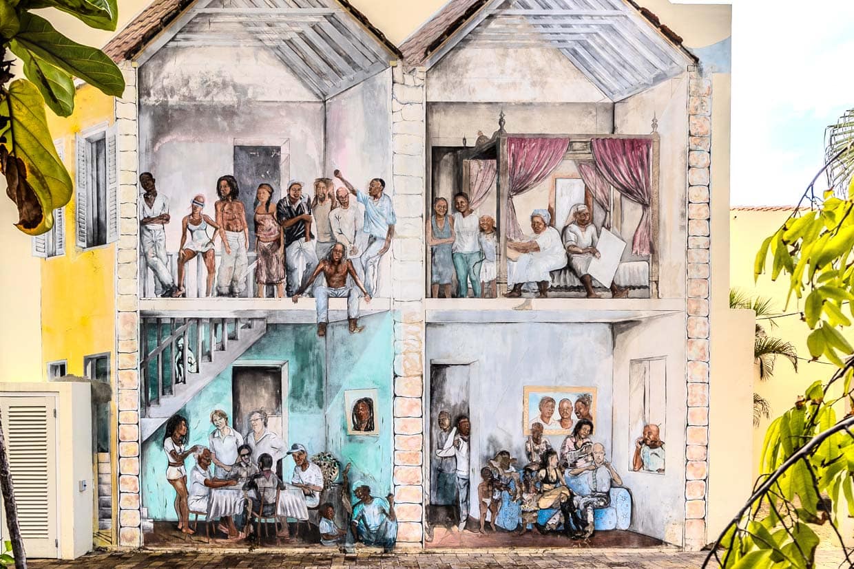 En una pared de la capital de Curaçao, una pintura personalizada muestra cuatro escenas típicas de la sociedad urbana de la época en que Willemstadt fue declarada Patrimonio de la Humanidad por la UNESCO / © Photo: Georg Berg